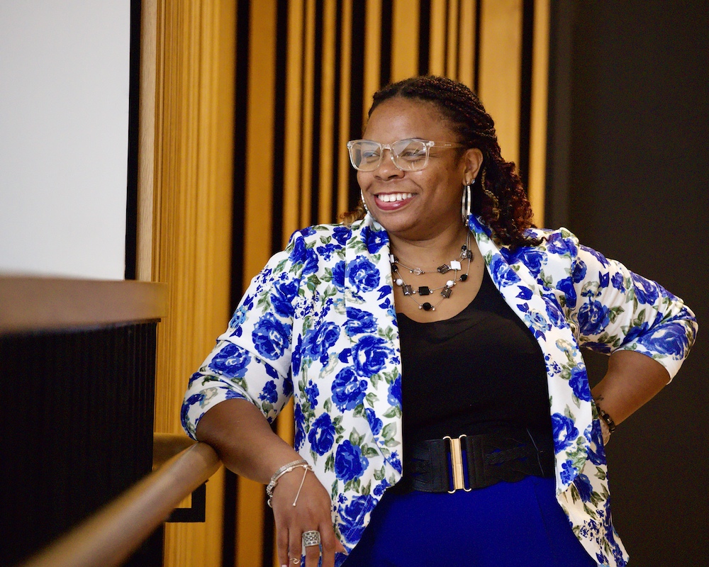 Author Charita D. Matthews smiling in blue, white & black outfit.